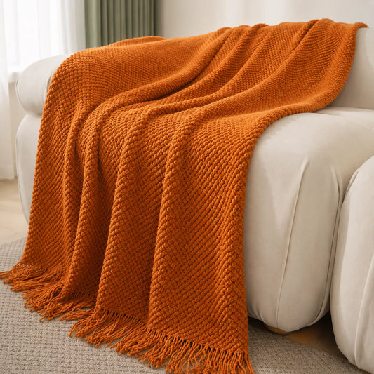 Burnt-orange herringbone knit throw blanket with tassels